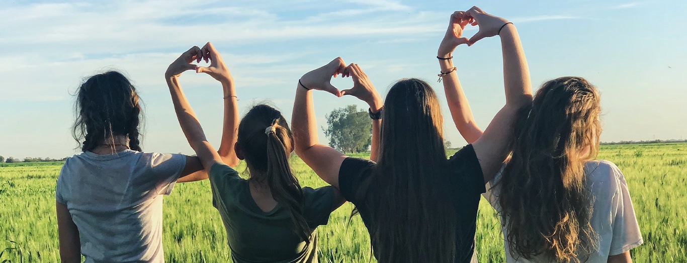 Group of women making heart signs above heads